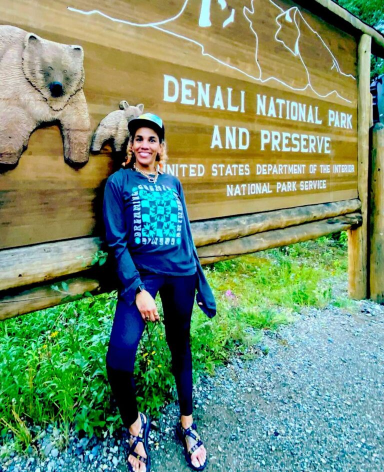 Woman standing next to the Denali National Park sign