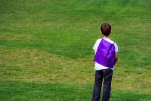 Boy with purple backpack in the grass